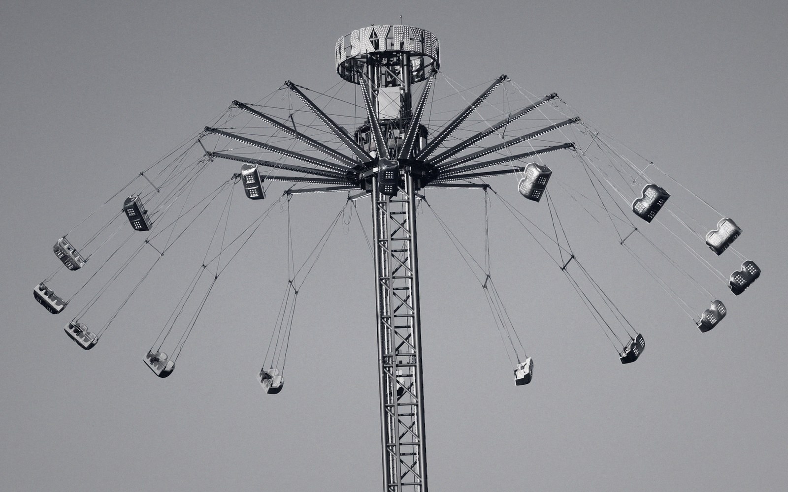Empty swing chairs dangle from cables atop a tall carnival swing tower ride