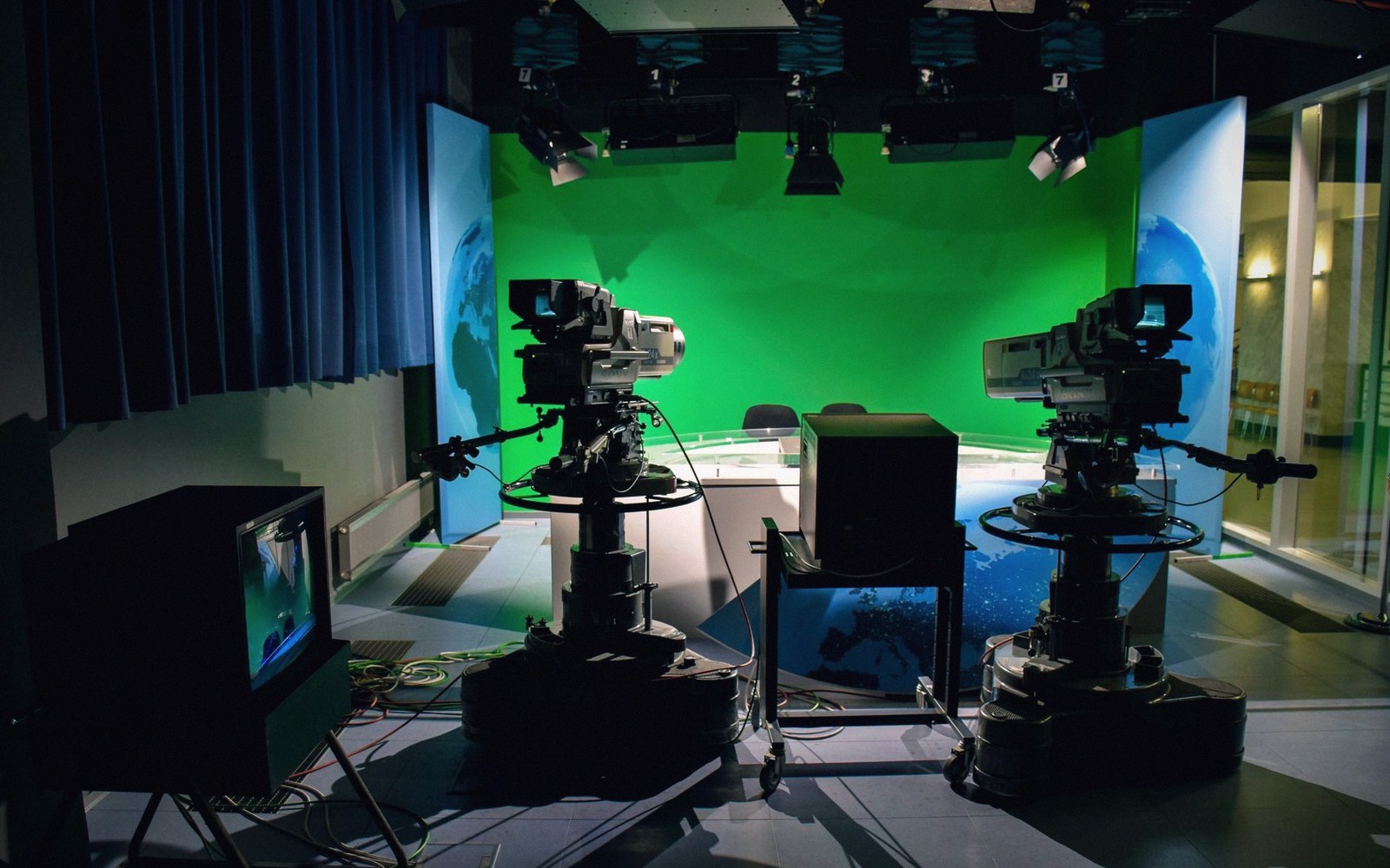 Television studio with a green screen backdrop flanked by two large broadcast cameras